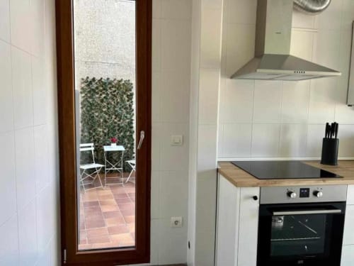 Cocina moderna en apartamento de Salamanca con estufa, campana y acceso a patio con vegetación