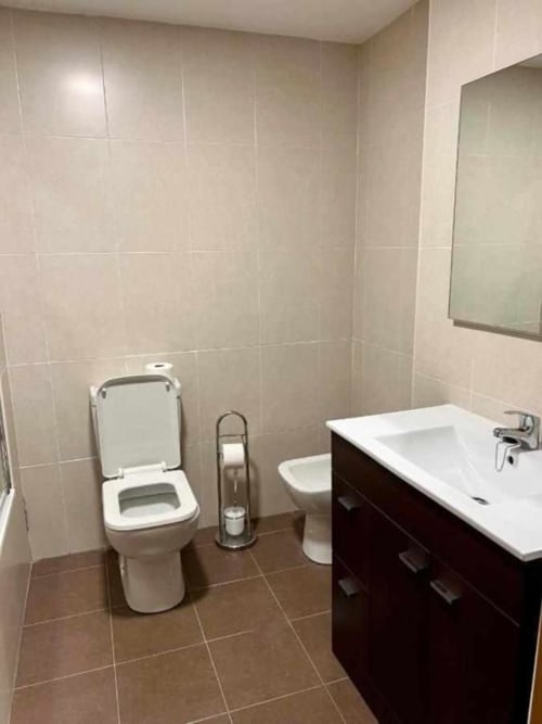 Moderno baño en apartamento de Salamanca con inodoro, lavabo, espejo y paredes alicatadas