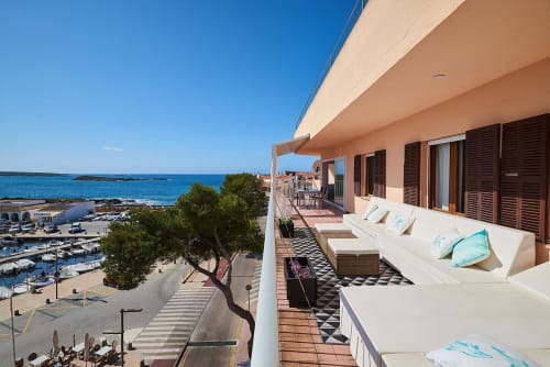 Terraza de hotel frente al mar con tumbonas con vistas a la marina y aguas turquesas en Colonia de Sant Jordi