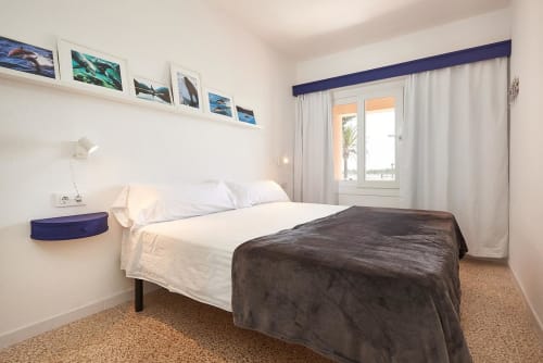 Bright modern bedroom with white bedding, navy accents, and sea views in Colonia de Sant Jordi hotel