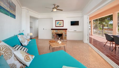 Bright beachside suite with turquoise bed, fireplace, and ocean-view terrace in Colonia de Sant Jordi