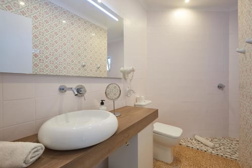 Modern bathroom with white oval sink, wooden vanity, and decorative patterned tiles in Colonia de Sant Jordi hotel