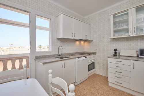 Modern kitchen with white cabinetry, granite countertop, and sea view at Colonia de Sant Jordi hotel
