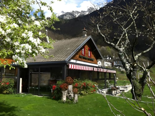 Locanda del Sasso Zimmer in Crodo, Italien: Alpines Chalet mit roter Markise, Bergblick und blühenden Gärten
