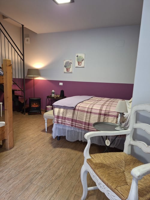 Cozy bedroom at Locanda del Sasso Rooms in Crodo with plaid bedding, purple accent wall, fireplace and rustic furnishings
