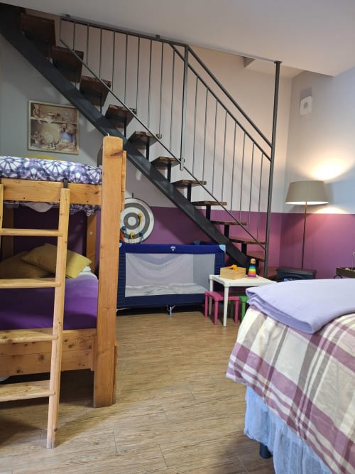 Colorful children's bedroom at Locanda del Sasso with bunk beds, play pen, and metal staircase to loft