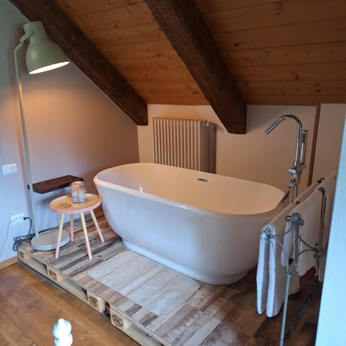 Luxurious freestanding bathtub in rustic apartment at Locanda del Sasso Rooms, Crodo with exposed wooden beams