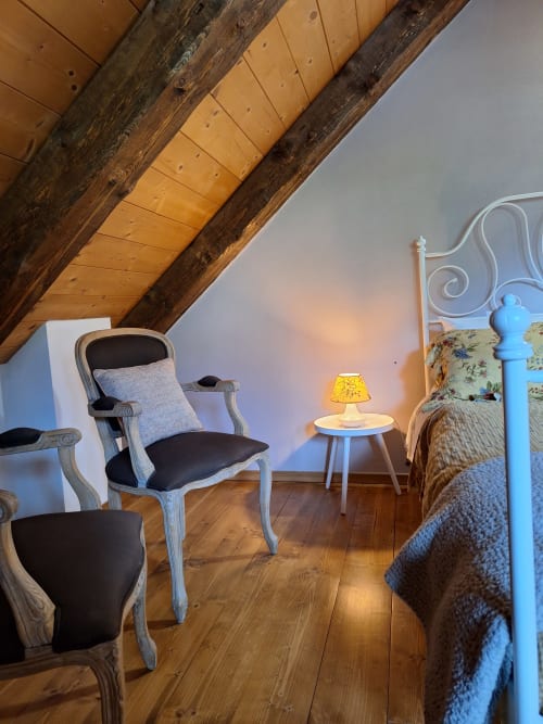Cozy attic apartment at Locanda del Sasso in Crodo with exposed beams, vintage chairs, and mountain views
