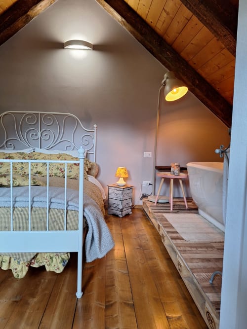 Cozy attic bedroom at Locanda del Sasso, Crodo Italy with white iron bed, wooden beams, and mountain views