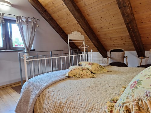 Cozy attic bedroom at Locanda del Sasso in Crodo with exposed beams, floral bedding, and mountain views