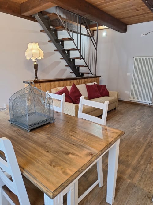 Cozy apartment living area at Locanda del Sasso with wooden table, sofa, stairs, and mountain views in Crodo