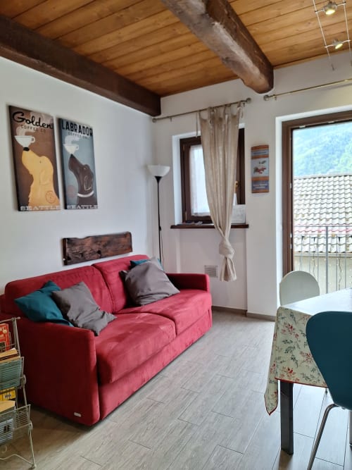 Accogliente soggiorno di appartamento di montagna con divano rosso presso Locanda del Sasso Rooms, Crodo Italia