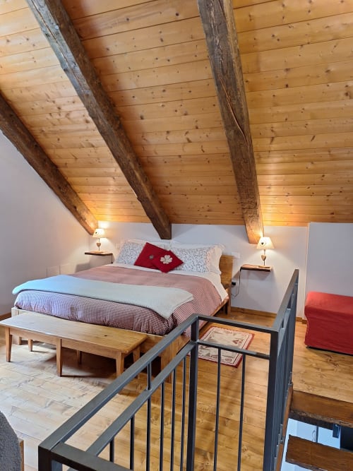 Cozy loft bedroom at Locanda del Sasso with exposed beams, modern furnishings, and mountain views in Crodo
