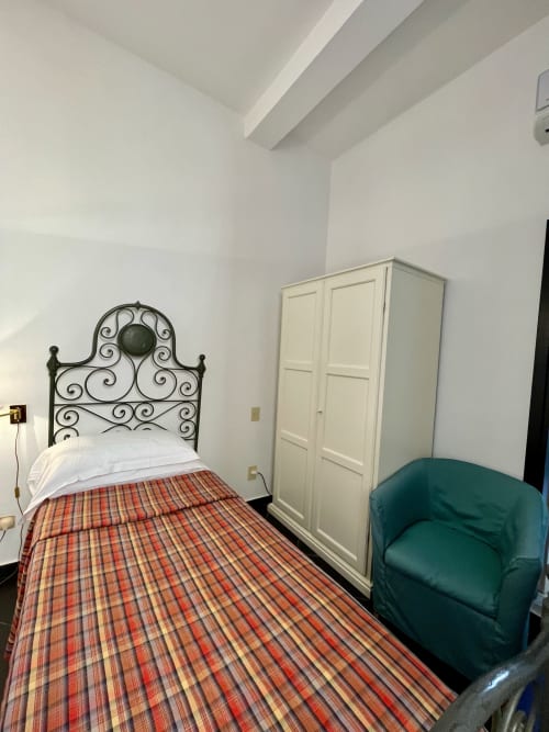 Chambre single à l'Hôtel Beau Rivage, Alassio, avec lit en fer forgé et fauteuil vert