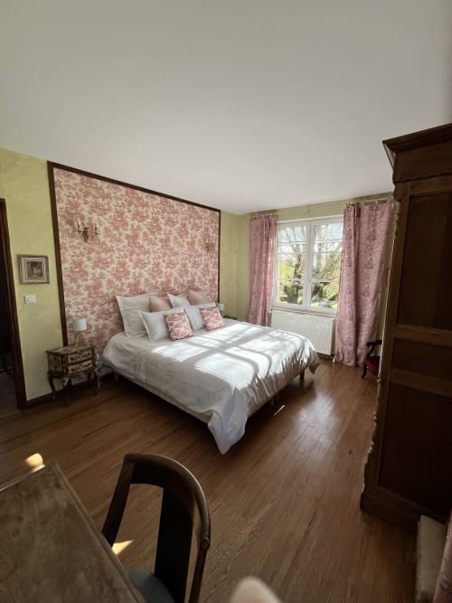 Chambre élégante du gîte Les Papillons de Baccara à Gondrin avec tête de lit fleurie rose et meubles en bois