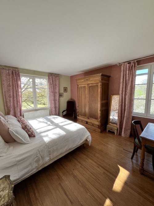 Chambre spacieuse de la maison d'hôtes Les papillons de baccara à Gondrin avec armoire en bois, lit blanc et vue sur la campagne