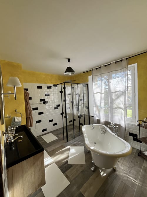 Salle de bain luxueuse aux murs jaunes, baignoire îlot et douche à l'italienne au gîte Les papillons de baccara, Gondrin