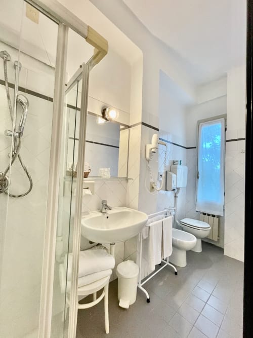 Modernes Badezimmer im Hotel Beau Rivage Alassio mit Dusche, Waschbecken, Toilette und beleuchtetem Spiegel
