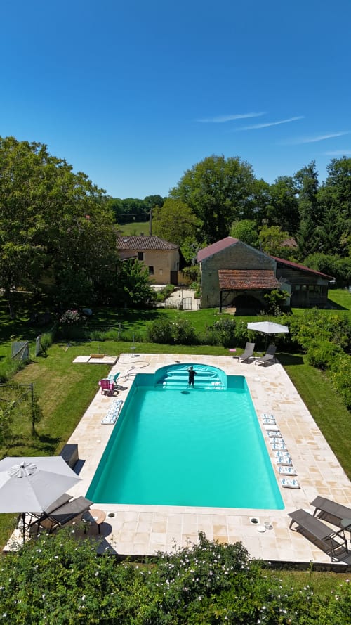 Piscine turquoise du gîte Les papillons de baccara à Gondrin avec transats et bâtiments historiques
