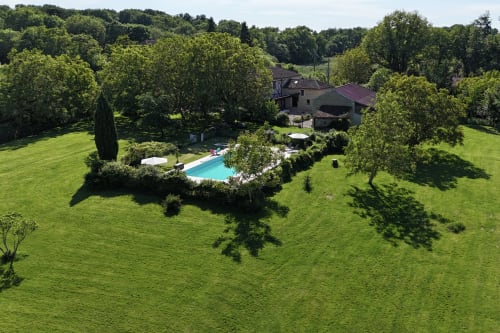 Vue aérienne du gîte Les papillons de baccara à Gondrin avec piscine turquoise, jardins soignés et forêt en arrière-plan