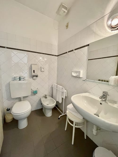 Sauberes Badezimmer im Hotel Beau Rivage in Alassio mit Toilette, Bidet, Waschbecken und weißen Fliesenwänden