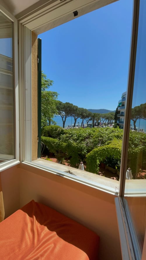 Blick aus einem Zimmer des Hotel Beau Rivage in Alassio auf Strand, Mittelmeer, Pinien und Berge an klarem Tag