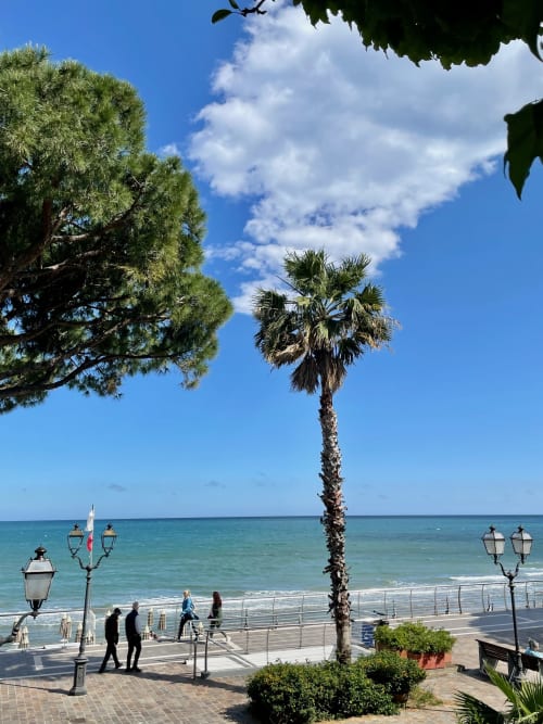 Strandpromenade von Alassio mit Palme, Meerblick und blauem Himmel beim Hotel Beau Rivage