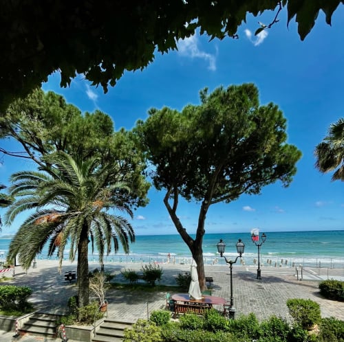 Hotel Beau Rivage Strandblick in Alassio mit Palmen, Sandstrand und kristallklarem Meer unter sonnigem Himmel