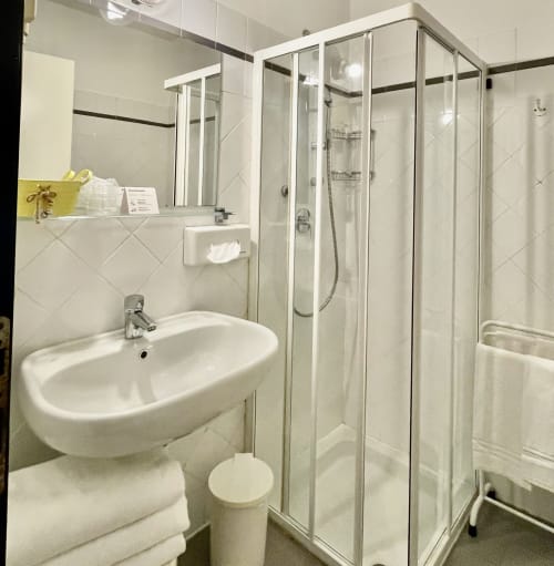 Modernes Badezimmer des Hotel Beau Rivage in Alassio mit weißem Waschbecken, Glasdusche und Ausstattung