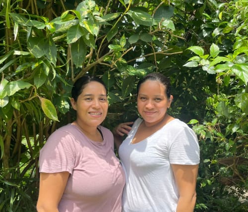 Two women smiling at Villa Mango B&B in Nosara, Costa Rica, surrounded by lush green vegetation