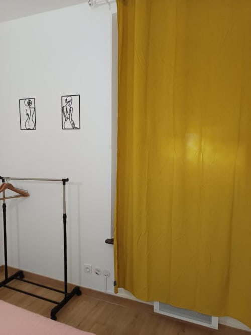 Coin dressing d'appartement avec rideau jaune, portant vêtements et art mural minimaliste à Pont-Sainte-Maxence