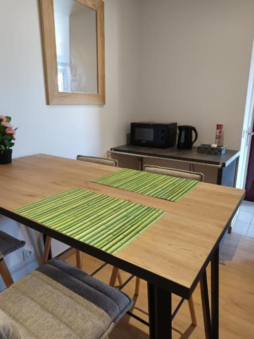 Table à manger contemporaine avec sets de table verts dans l'appartement de Pont-Sainte-Maxence, coin cuisine visible