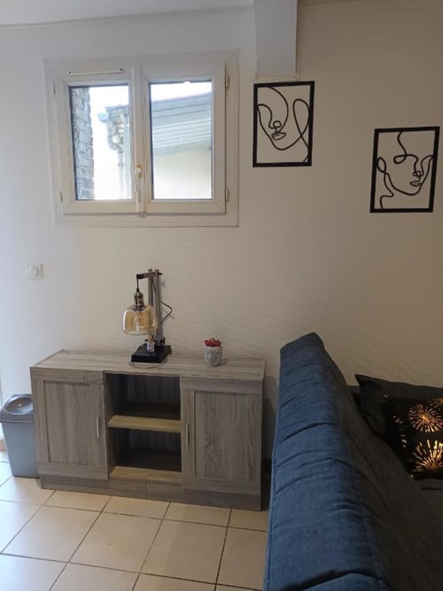 Salon d'appartement moderne avec canapé bleu, meuble en bois, fenêtre et art mural minimaliste à Pont-Sainte-Maxence
