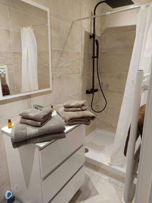 Salle de bain moderne à Location Saisonnière Pont-Sainte-Maxence avec douche à l'italienne, meuble vasque blanc, miroir et serviettes pliées