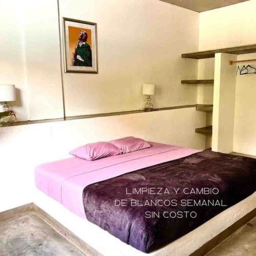 Ropa de cama rosa y oscura en la cama de la moderna cabaña Casa Tsuki en Calilla & Tsuki, Puerto Escondido