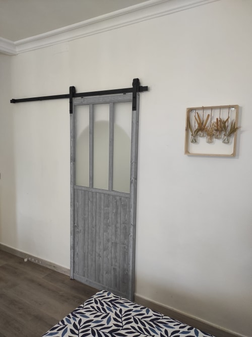 Chambre du gîte Accolade à Châteaudun avec porte grange coulissante, murs blancs et tapis à motifs