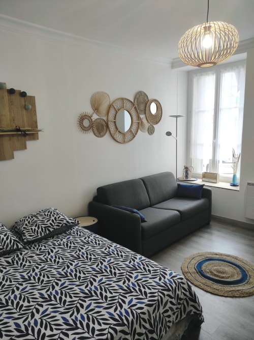 Studio contemporain à l'Accolade Châteaudun avec canapé noir, lit à motifs et décoration murale tissée vue sur la ville