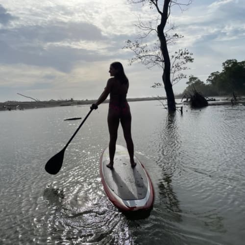 Woman paddleboarding in Nosara, Costa Rica near Villa Mango B&B with tropical coastline and trees