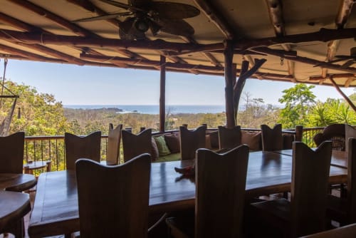 Villa Mango B&B terrace in Nosara with ocean views, wooden furniture, and palm trees