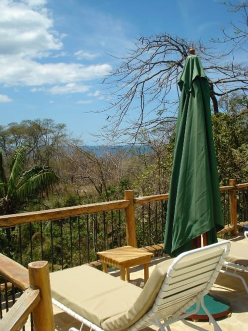 Villa Mango B&B deck with lounge chair, green umbrella, and mountain views in Nosara, Costa Rica