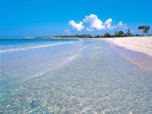Mar turquesa immaculat i platja d'arena blanca a Colònia de Sant Jordi amb cel blau clar i núvols blancs