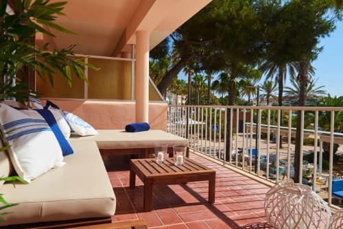 Terrassa de l'apartament SAND amb vistes al mar, zona de descans, taula de fusta i palmeres a Colònia de Sant Jordi