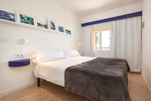 Dormitori lluminós a l'Apartament SAND, Colonia de Sant Jordi amb vistes al mar, roba de llit blanca, manta fosca i accés a terrassa