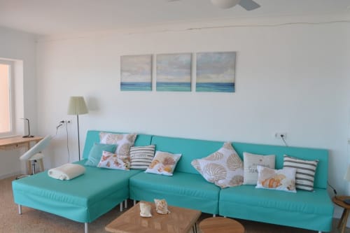 Sofà turquesa brillant amb coixins decoratius en apartament modern amb vistes al mar a Colònia de Sant Jordi