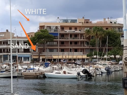 Vista marina de Colonia de Sant Jordi amb velers, edificis de platja color sorra i apartaments vora mar