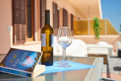 Botella i copes de vi blanc sobre taula blava a l'apartament primera línia de mar de Colonia de Sant Jordi amb terrassa amb vistes al mar