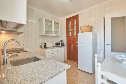 Cuina moderna amb taulells de granit, electrodomèstics blancs i vista al mar a l'apartament WHITE de Colonia de Sant Jordi