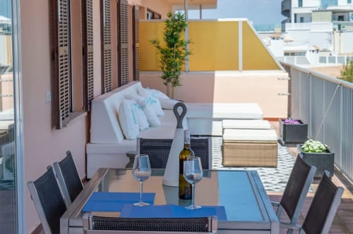 Terrassa d'apartament a primera línia de mar a Colònia de Sant Jordi amb taula de menjador, copes de vi, gandules i vistes al mar