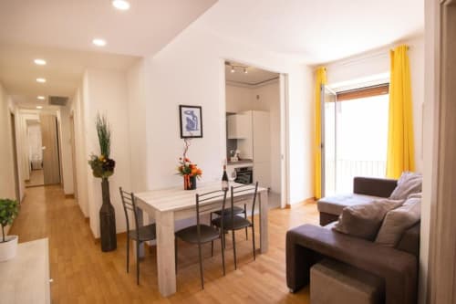 Appartamento Dimore Verona moderno con living open-plan, zona pranzo, cucina, divano marrone, tende gialle e pavimenti in legno