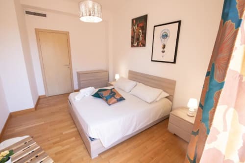 Camera da letto moderna dell'appartamento Dimore Verona a Verona con pavimenti in legno, biancheria bianca e arredamento con vista città